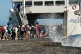 People boarding the ferryboat Daskalogiannis in Agia Roumeli on a stormy day. Waves are crashing on the jetty sending spray onto the queuing crowd